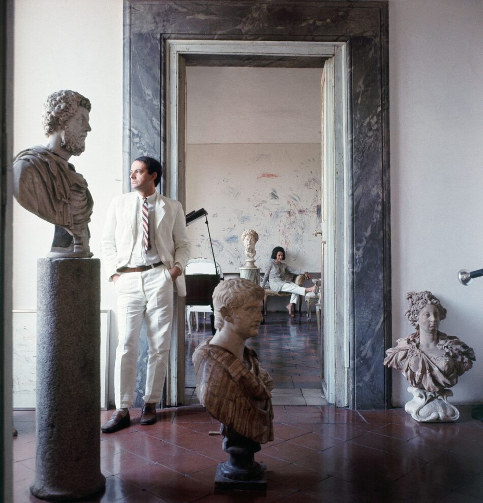 Cy Twombly in abito bianco in piedi tra busti di marmo antico all interno di un lussuoso palazzo nobiliare romano