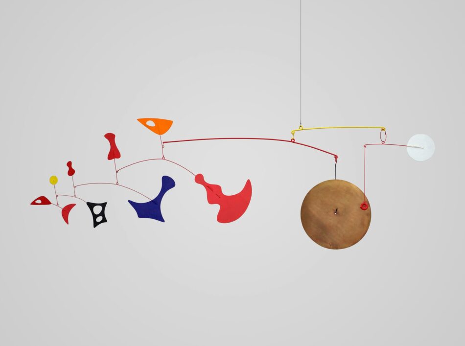 Scultura mobile di Alexander Calder con elementi geometrici colorati e un grande disco metallico dorato su sfondo grigio chiaro