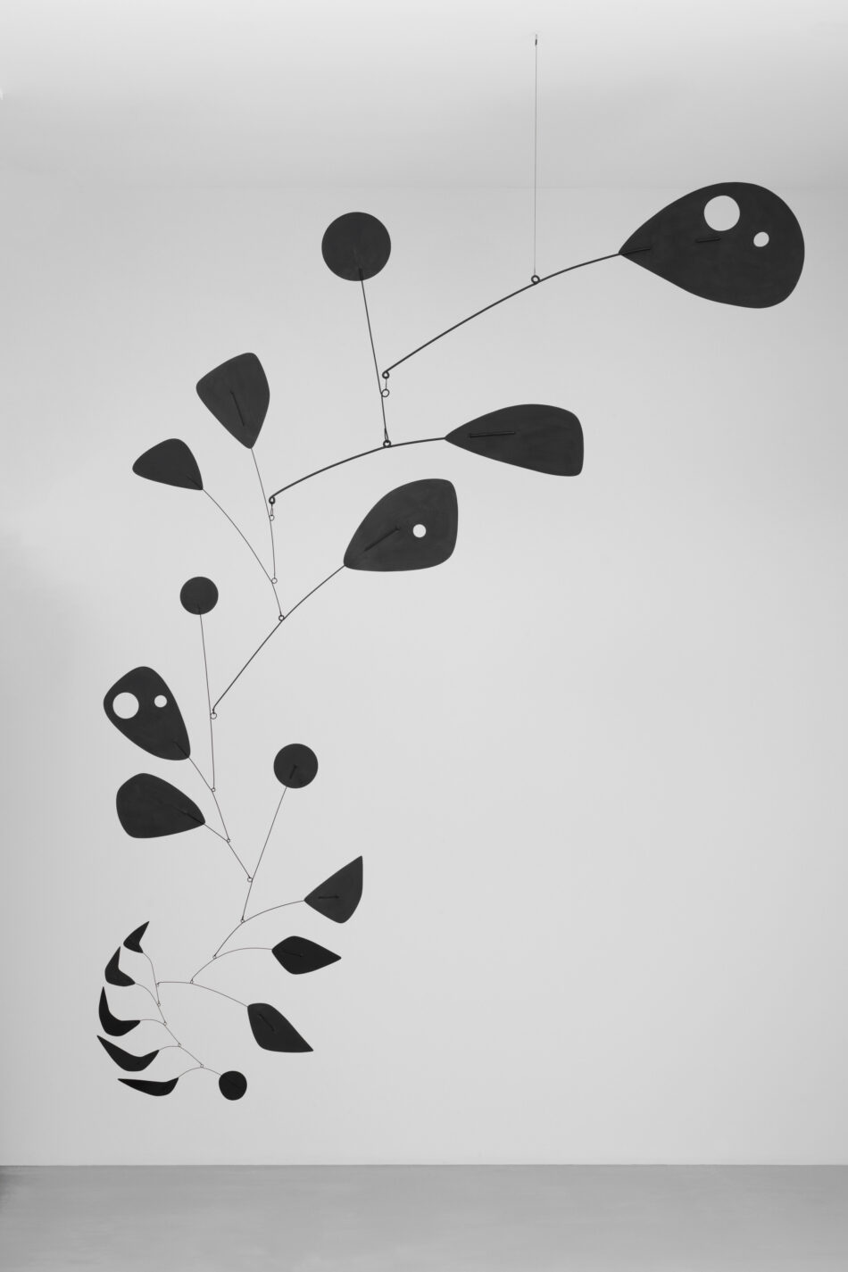 Scultura mobile interamente nera di Alexander Calder appesa al soffitto contro una parete bianca