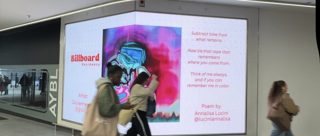 Grande schermo digitale angolare in un corridoio urbano moderno che mostra uno spettrogramma psichedelico nei toni del fucsia, blu e viola. Accanto all'immagine compare il testo poetico in inglese di Annalisa Lucini e il logo del progetto "Billboard Residency". Due passanti in movimento sfocano parzialmente l'inquadratura.