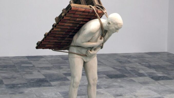 Scultura di un uomo nudo curvato in avanti che trasporta sulla schiena un tetto di tegole legato con corde.